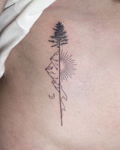 a woman's chest with a tattoo on it that has a pine tree in the middle