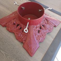 a red vase sitting on top of a wooden table next to a pair of scissors