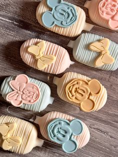 mickey mouse cookie cutters are lined up on a wooden table, ready to be decorated