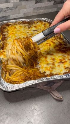 a person using a spatula to scoop some food out of a casserole dish