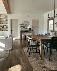 a dining room table and chairs in front of a window with open shelves on either side