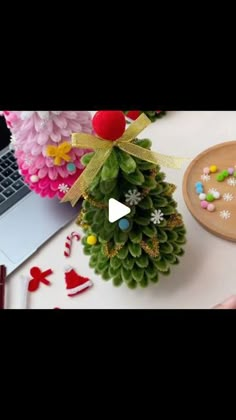 a pine cone christmas tree sitting on top of a desk next to a laptop computer