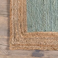 an area rug with blue and tan colors on top of a wooden floor next to a wall