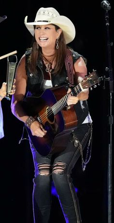 a woman with a cowboy hat and guitar on stage