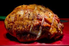 a cooked ham on a red plate with a knife