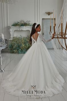 a woman in a white wedding dress standing next to a chandelier