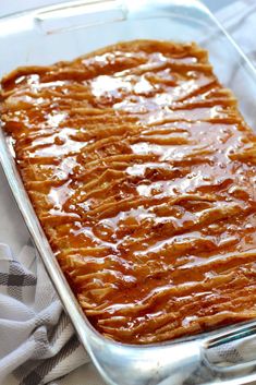 a casserole dish is covered with caramel sauce and sits on a towel