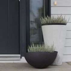 two large planters sitting on top of a wooden floor next to a black door