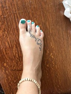 a woman's foot with tattoos on it sitting next to a wooden table and flowers