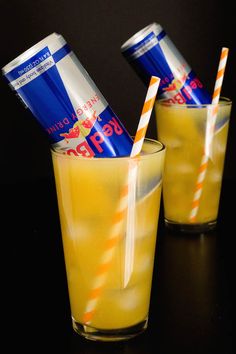 two glasses filled with drinks sitting on top of a black table next to each other