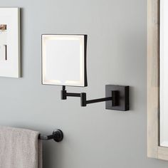 a bathroom mirror mounted to the side of a wall next to a towel rack with a light on it