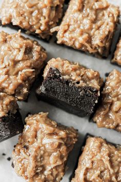 chocolate brownies with peanut butter frosting are arranged in rows on a piece of parchment paper