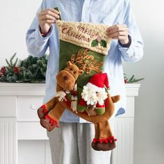 a man holding up a christmas stocking with reindeers on it