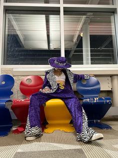 a person sitting on top of a bench in front of some colorful chairs and windows