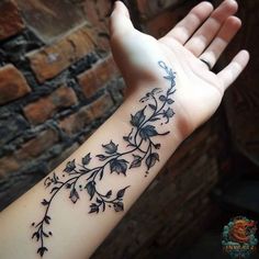 a woman's arm with flowers and vines on the left side of her hand