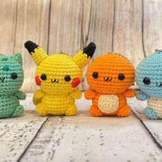 four crocheted stuffed animals sitting next to each other on a wooden table with wood planks