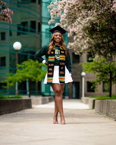 a woman in a graduation outfit standing on the sidewalk