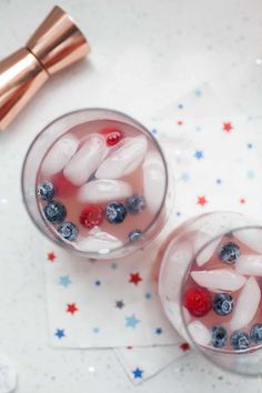 two glasses filled with ice and berries on top of a table