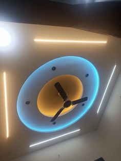 a clock that is mounted to the ceiling in a room with neon lights on it