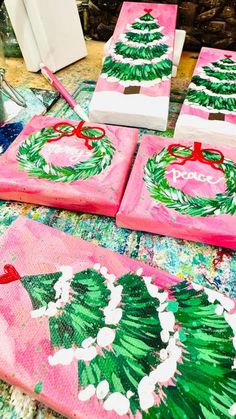 three pink christmas coasters with green and red designs on them, sitting on a table in front of a fireplace