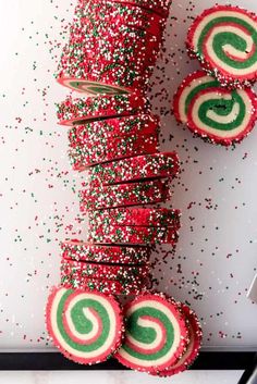 red, green and white candy canes are stacked on top of each other with sprinkles