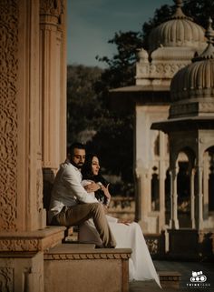 a man and woman sitting on a bench in front of a gazebo