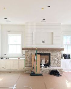 a living room with a fire place and some cabinets in the back ground that is being remodeled