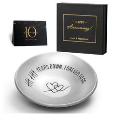 a silver bowl with the words happy anniversary written on it and a black box next to it