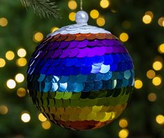 a multicolored ornament hanging from a tree with lights in the background