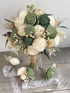 a bridal bouquet with white and green flowers on a wooden table next to lace