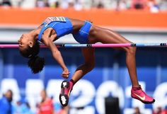 a woman jumping over a high bar in a competition