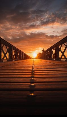 the sun is setting over a bridge that has been made to look like it's going