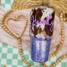 a purple and blue glitter tumbler sitting on top of a checkered tablecloth