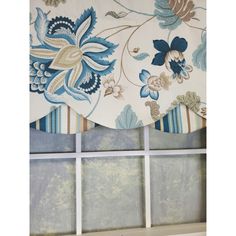 a window with blue and white flowers on it's valance hanging from the side