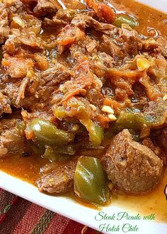 a white plate topped with meat and vegetables covered in gravy on top of a table