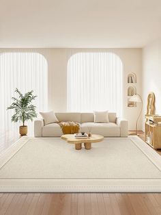 a living room with white furniture and large windows in the backround, along with a rug on the floor