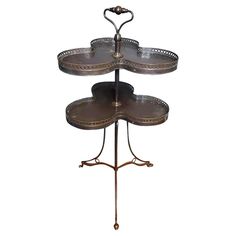 three tiered tray with metal handles and two plates on each side, sitting on a stand