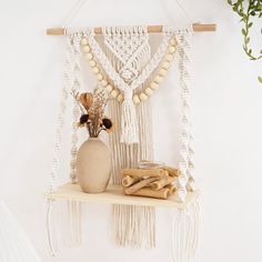 a white macrame hanging on a wall next to a vase