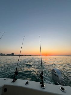 two fishing rods on the back of a boat at sunset