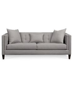 a gray couch with four pillows on it's back and one arm facing the camera