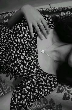 a black and white photo of a woman laying on a bed with her hand on her chest