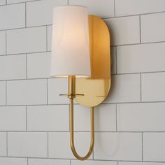 a wall light with a white shade on it's side against a brick wall