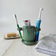 two toothbrushes in a green cup next to a towel