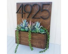 a wooden house number sign with succulents in it