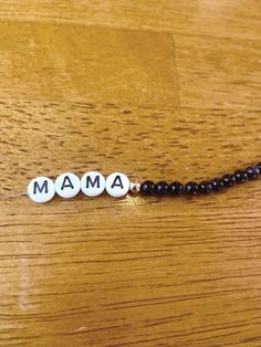 a beaded name necklace with the word mama spelled in white letters on black beads