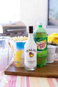 two bottles of liquid and some other ingredients on a cutting board next to a blender