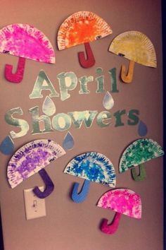 an art project with paper umbrellas and the words,'april showers'written on it