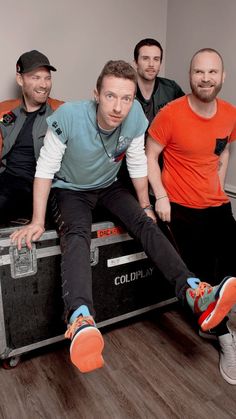 three men sitting on top of an old suitcase