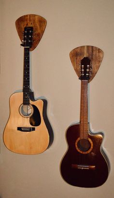 two guitars are hanging on the wall next to each other, one is made from wood