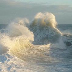 a large wave crashing into the ocean on a sunny day